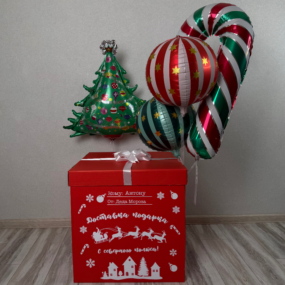 Коробка с бантом и надписью, внутри коробки 2 сферы, рядом Новогодняя ёлочка и Леденец