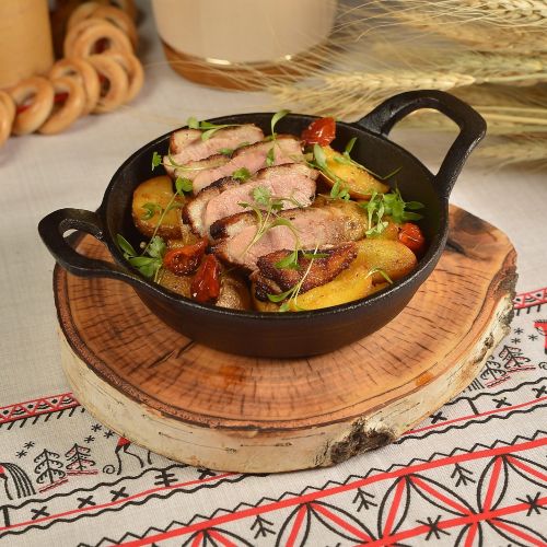 Утиная грудка на сковороде с картофелем, жаренным с луком.