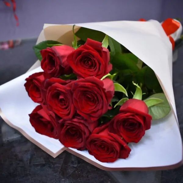 Букет из 9 темно-красных роз в белой бумаге с алой лентой